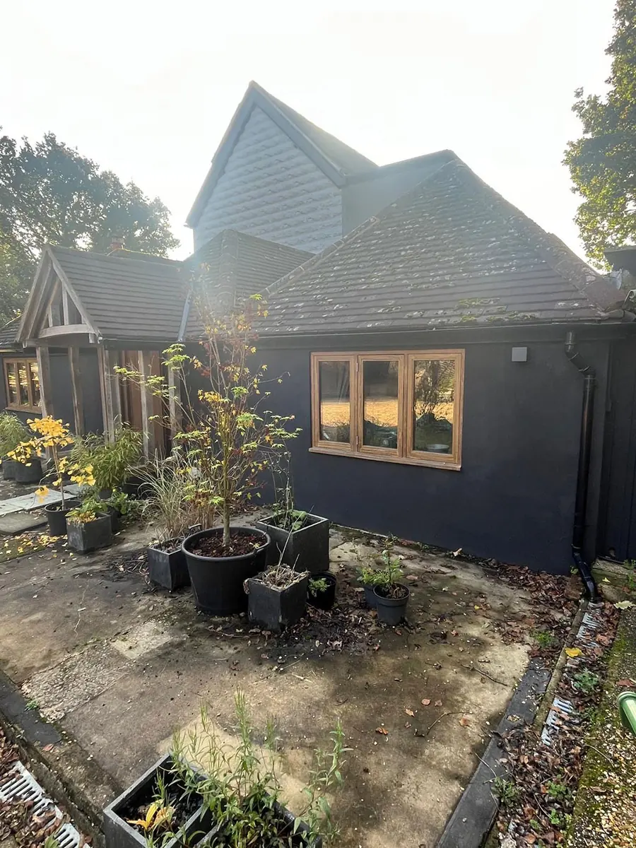 A dark clad annexe with oak windows, seen from the side