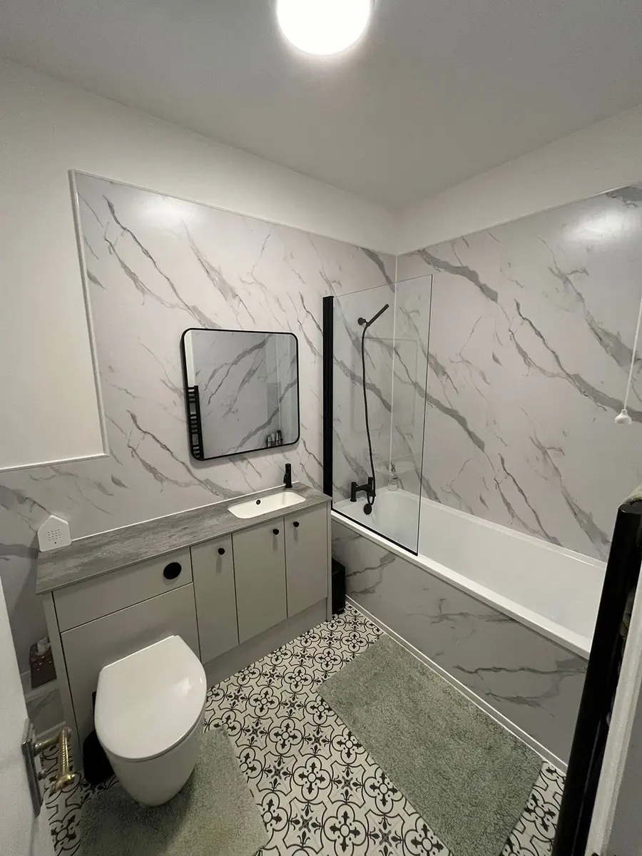 A marble tiled bathroom with black fittings and a patterned floor
