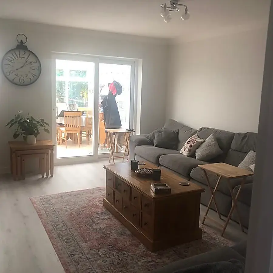 A finished living room with wood effect flooring and doors onto a conservatory