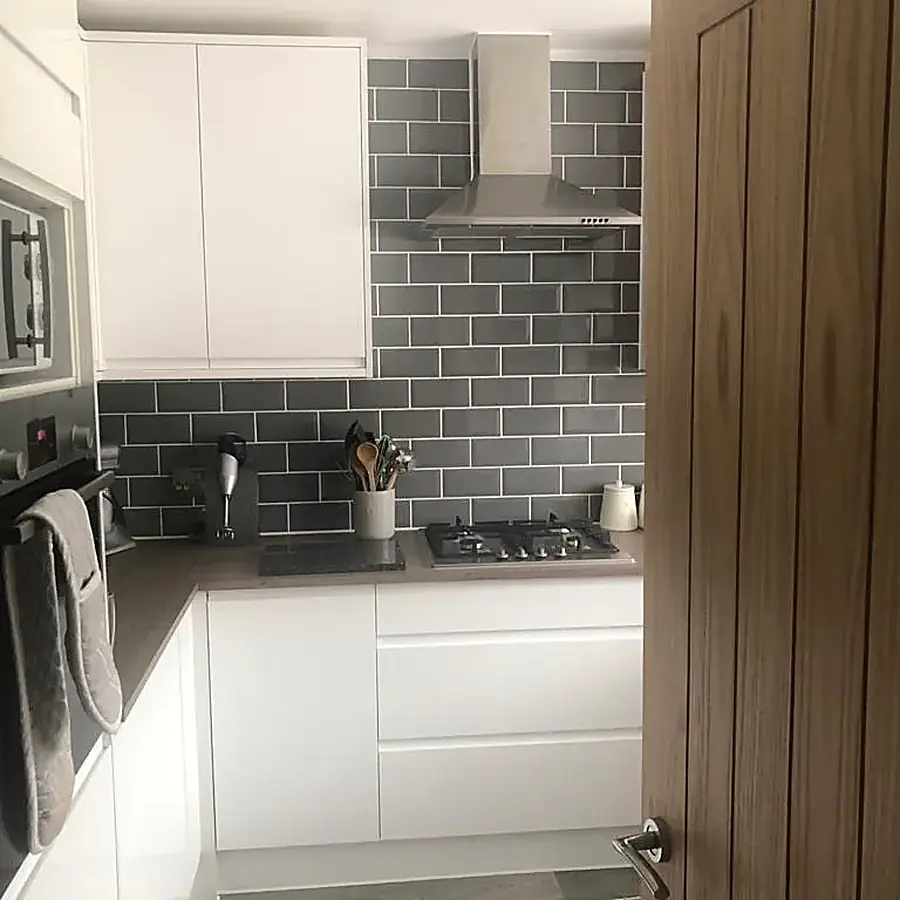 A white gloss kitchen with grey metro tiles and a dark worktop