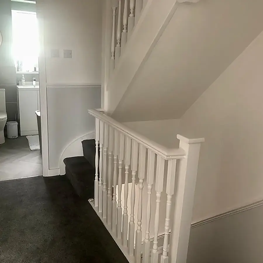 A freshly decorated hall with white spindles and a dark carpet
