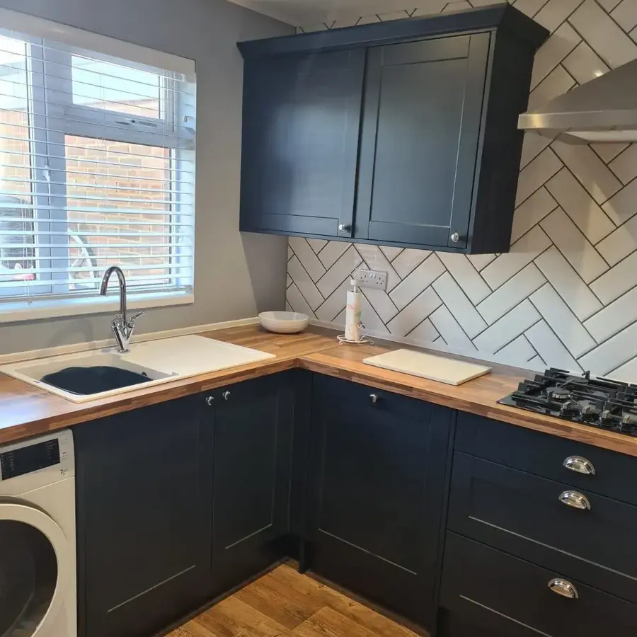 A navy shaker kitchen with oak worktop and a washing machine below