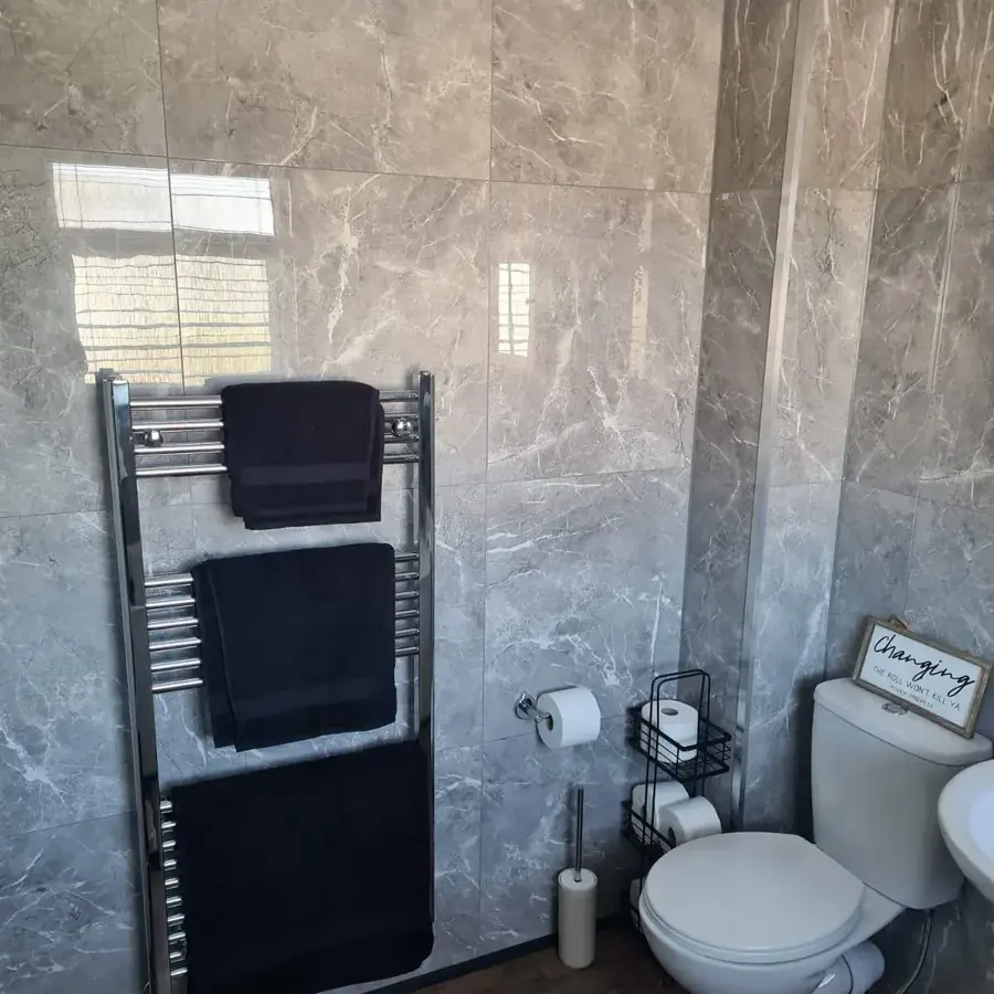 A grey marble effect bathroom with a black heated towel rail