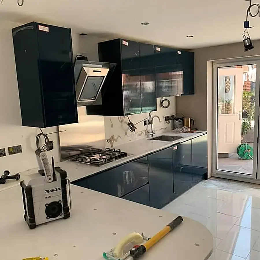 A navy gloss kitchen part way through fitting, with tools on the worktop