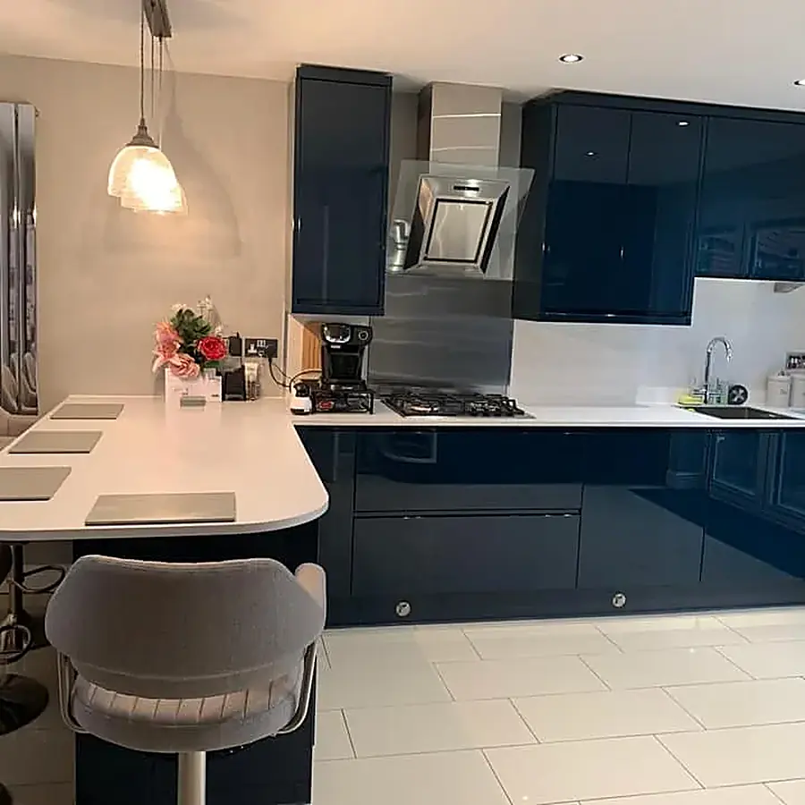 A navy gloss kitchen with a curved white island and bar stools