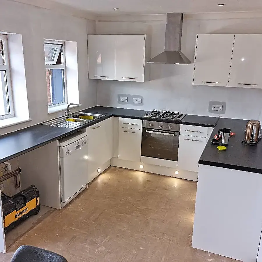 A white kitchen with a black worktop and downlights