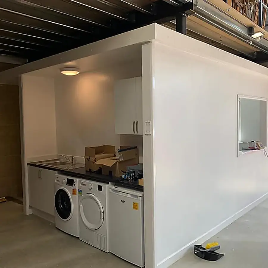 A garage converted into a utility space with white units and a washing machine