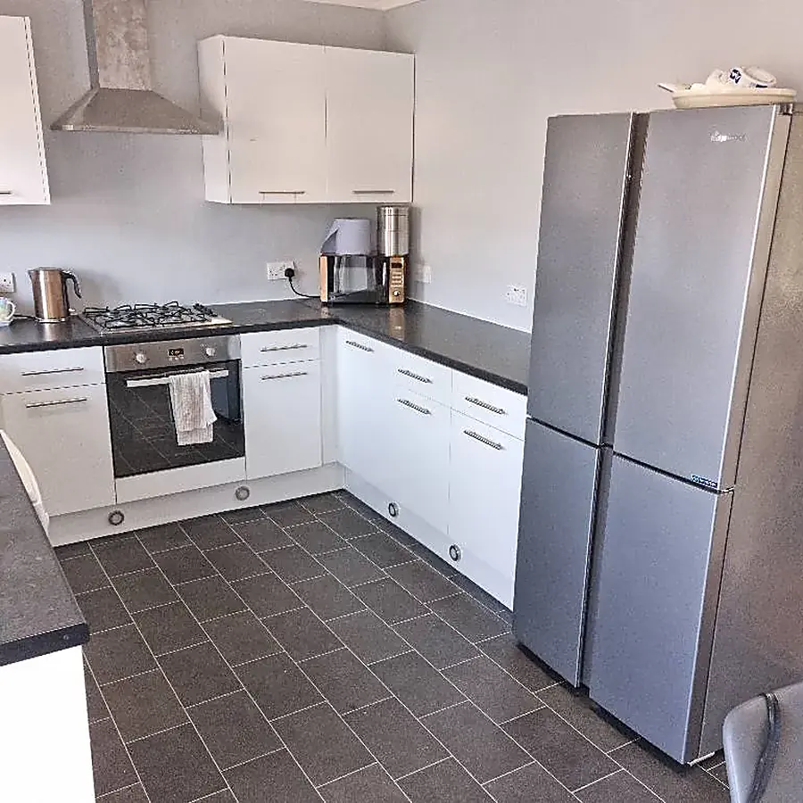 A white kitchen with a dark worktop and a tall silver fridge freezer