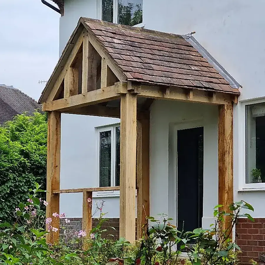 A green oak framed porch with a tiled roof on a rendered house