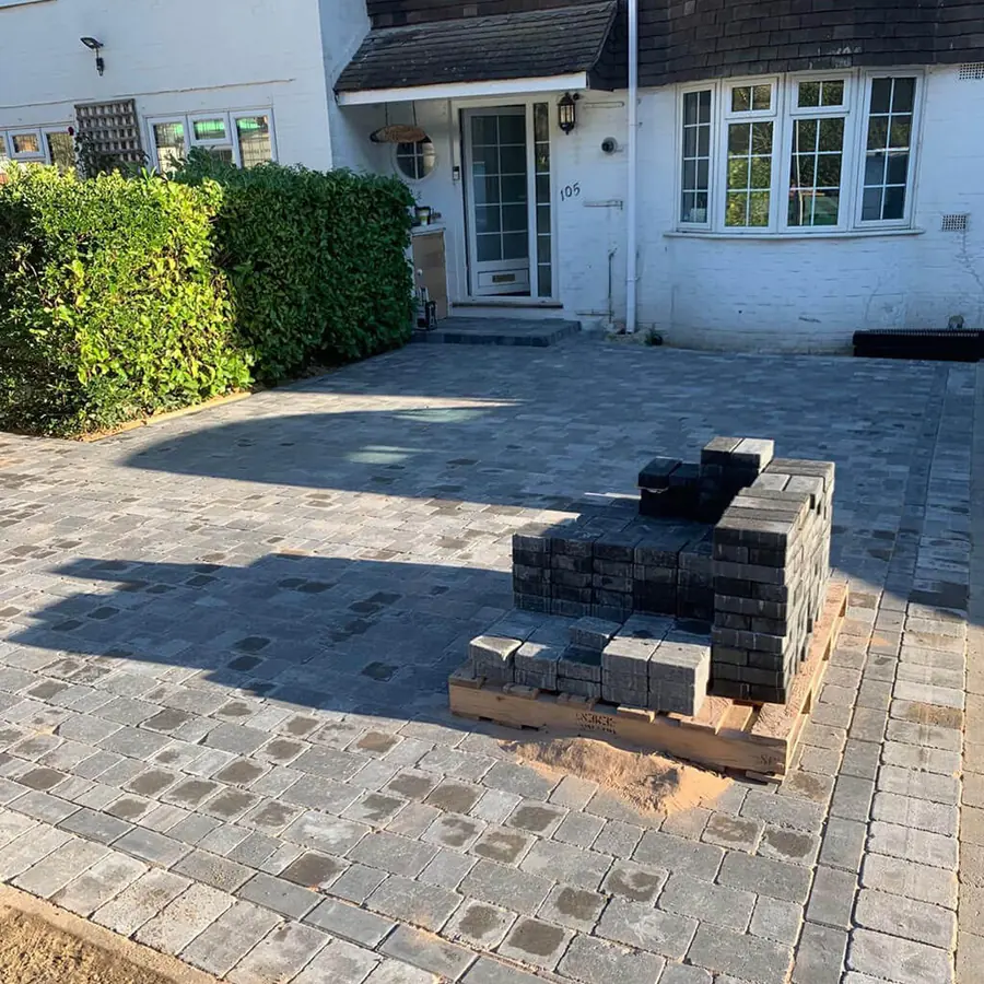 A charcoal and grey block paved driveway in front of a house