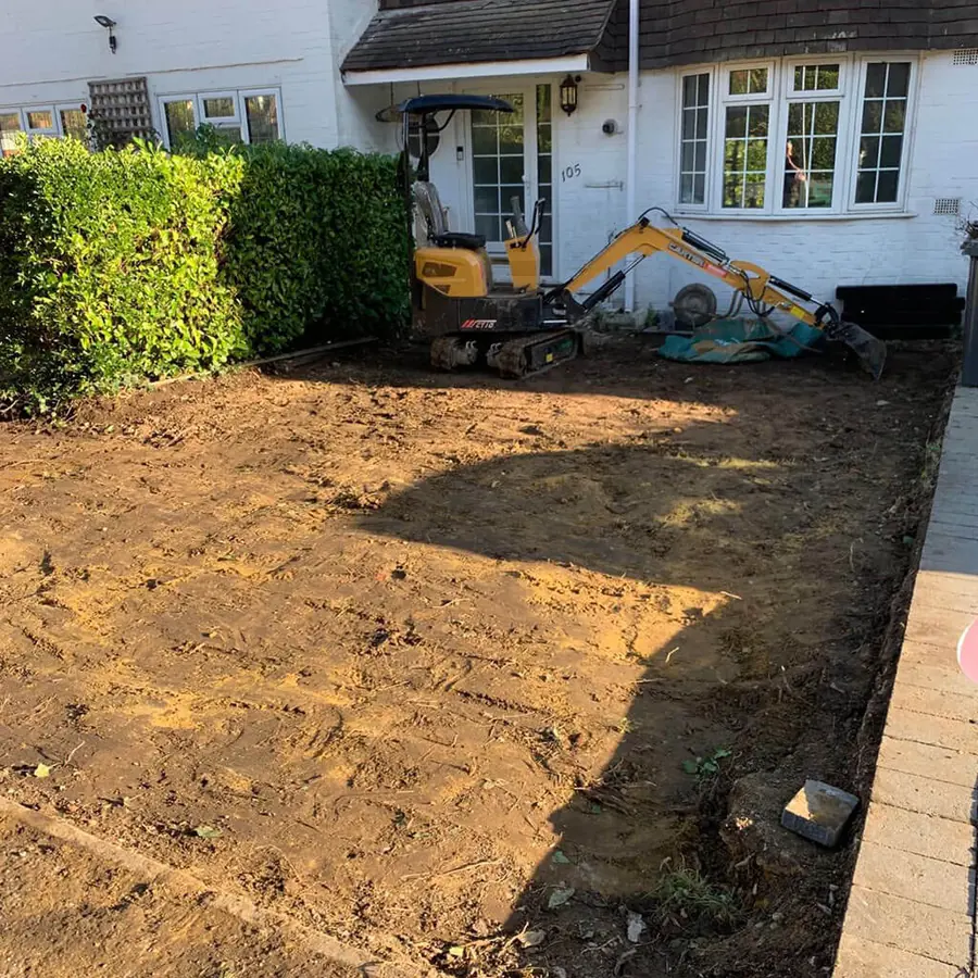 A mini digger excavating a front garden ready for foundations
