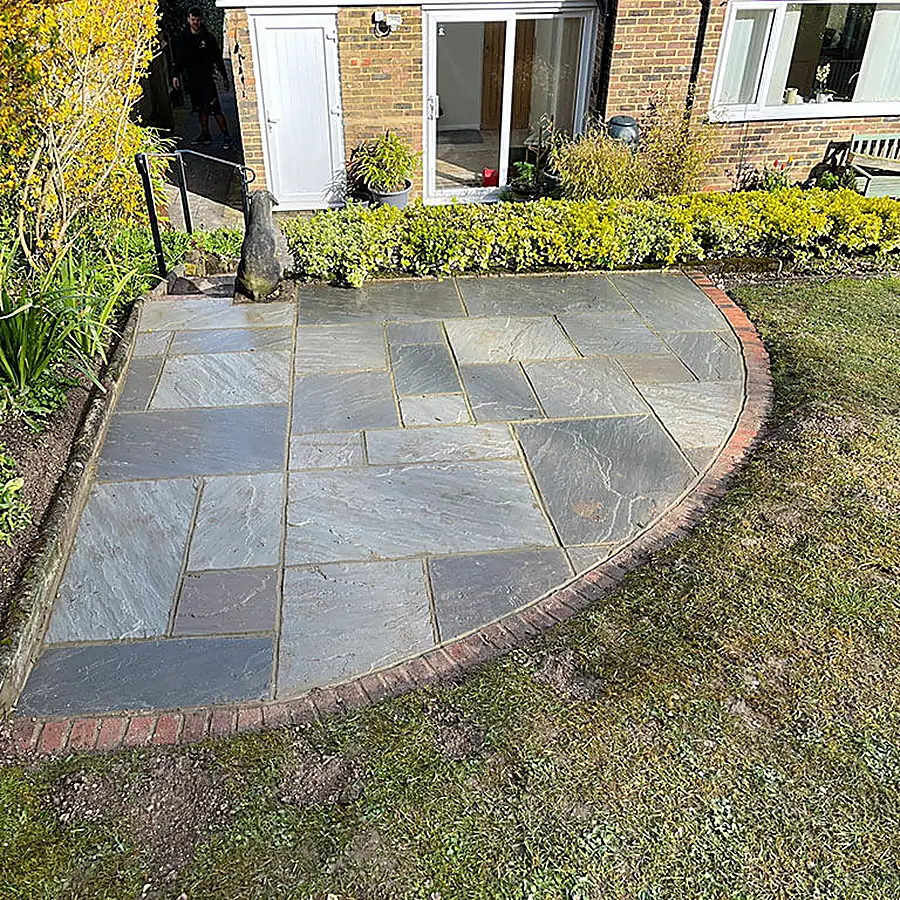 A circular Indian sandstone patio with brick edging