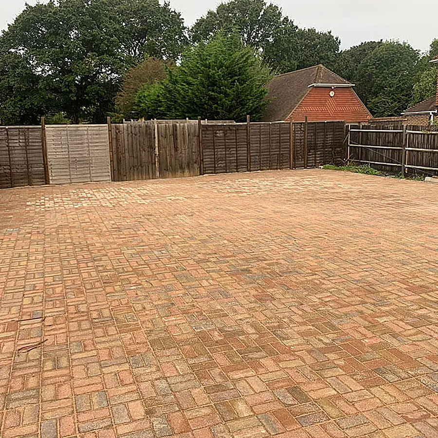 A large block paved area enclosed by close board fencing