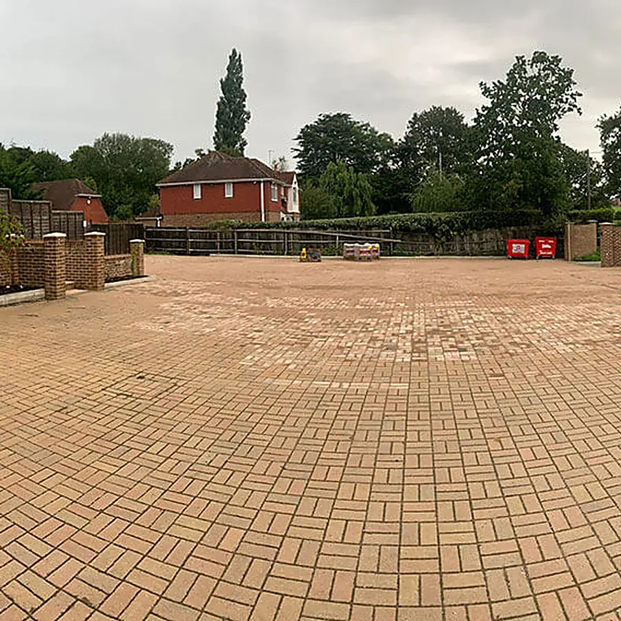 A block paved driveway leading to a rendered bungalow