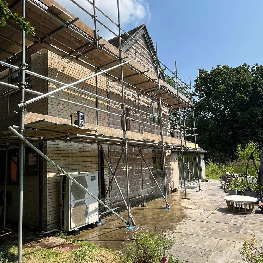 A rendered house under scaffold with a rear extension under way