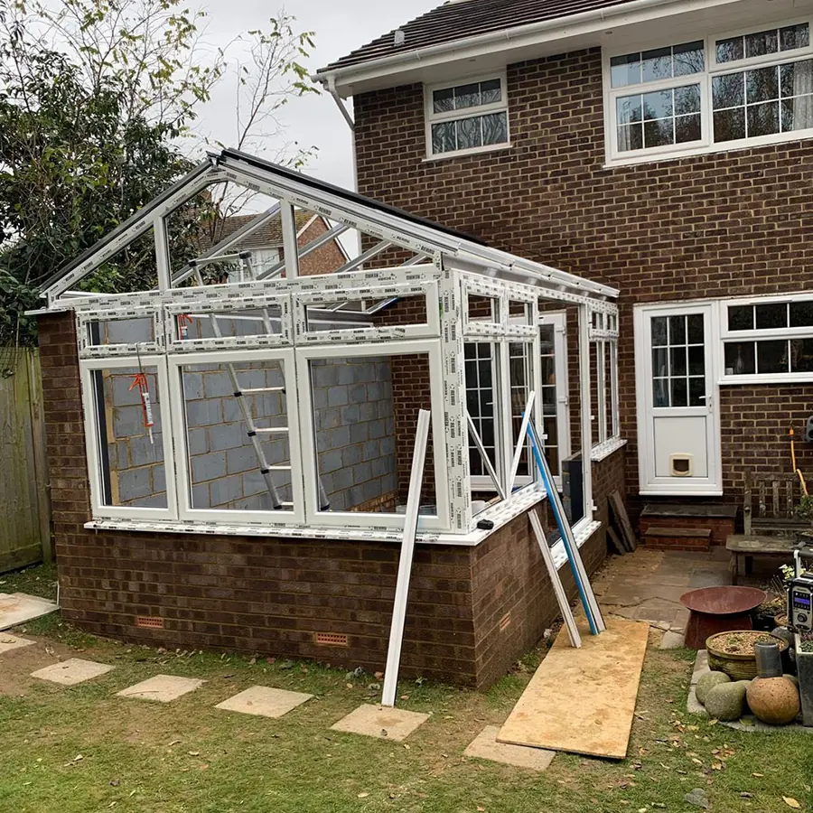 A conservatory frame going up on a brick base at the rear of a house
