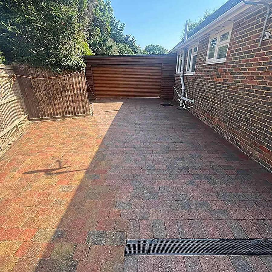 A block paved driveway with a new fence and a garage