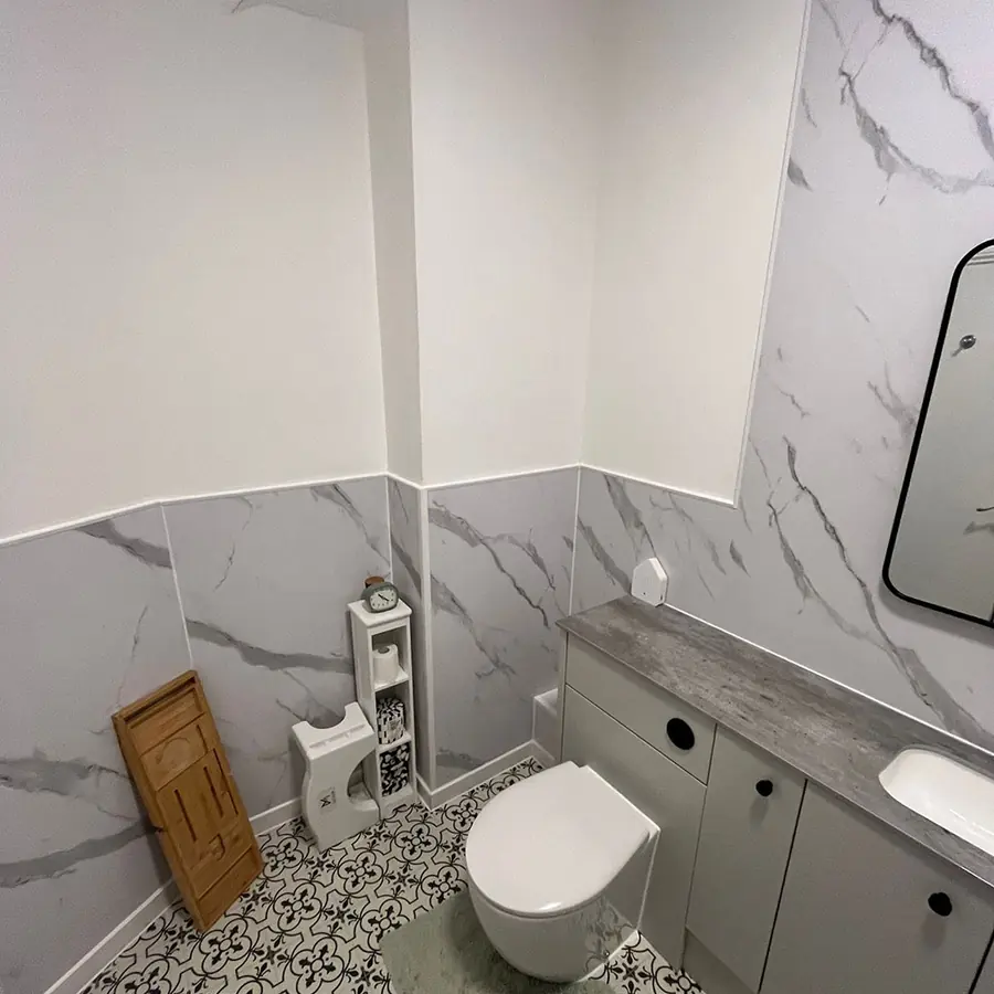 A marble tiled bathroom with a patterned floor and wall hung toilet
