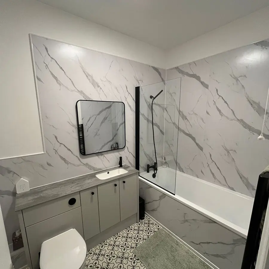 A marble tiled bathroom with black fittings and a grey vanity unit