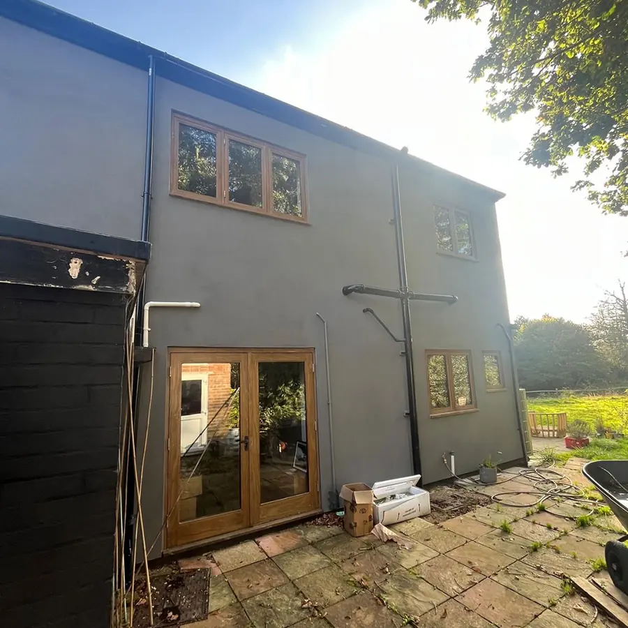 A rendered rear extension with oak framed windows in low sun