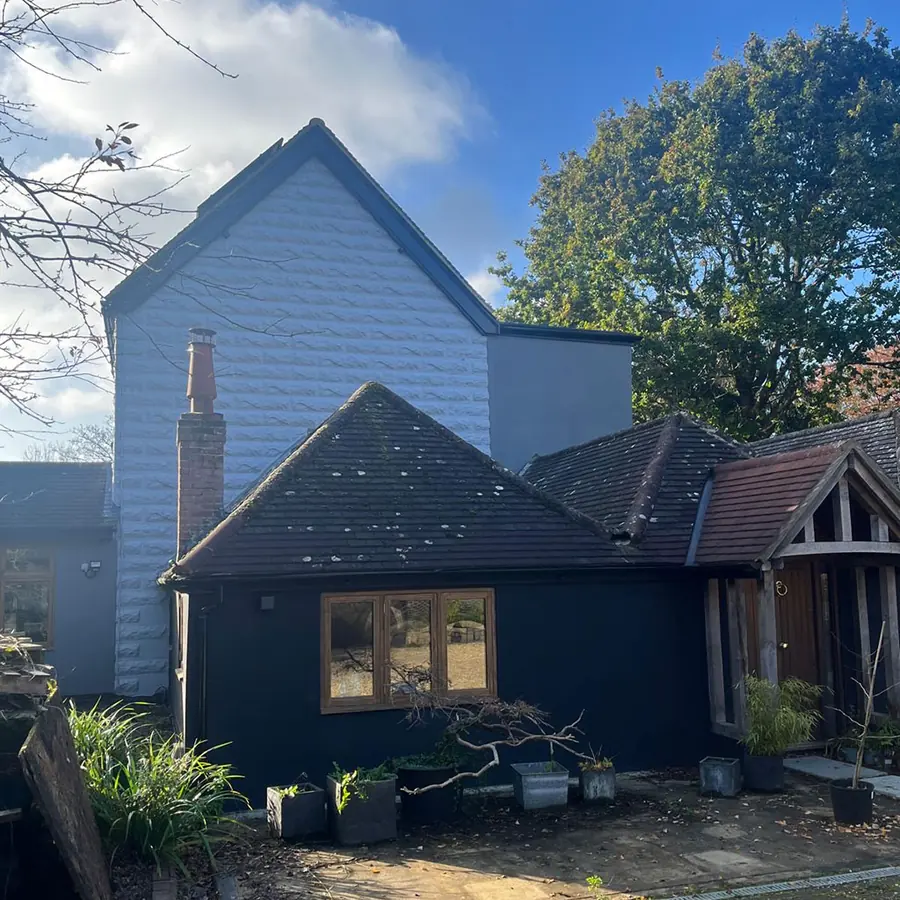 A dark timber clad annexe with oak windows and an oak porch